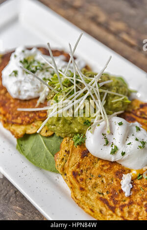 Brunch-Idee; Pfannkuchen mit Guacamole, Spinat und Spiegeleiern. Garniert mit Petersilie, Kürbiskerne und Pfeffer Stockfoto