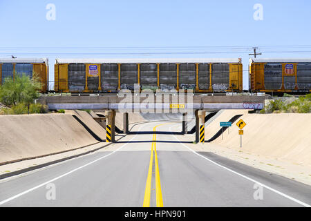 Gila Bend, USA - 25. Mai 2015: Union Pacific Güterzug auf einer Brücke über eine Straße in Gila Bend. Stockfoto