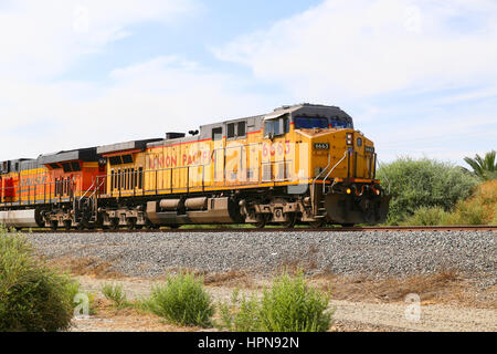 Mekka, Kalifornien, USA - 26. Mai 2015: Güterzug mit Union Pacific und BNSF-Motoren auf dem richtigen Weg neben California State Route 111. Stockfoto