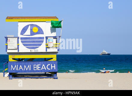 MIAMI BEACH, USA - 9. Mai 2015: Ein Abschnitt des Strandes mit eine Strandwache und einige Leute zum Sonnenbaden oder schwimmen, eine Yacht auf dem Meer in der ba Stockfoto