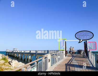 MIAMI BEACH, USA - 9. Mai 2015: Der Eingang zum South Pointe Pier mit einigen Leuten auf dem Pier. Der Eingang zum Hafen von Miami ist in den Rücken. Stockfoto