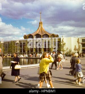 Blick auf das Gold gewölbt Vatikan Pavillon an einem anstrengenden Nachmittag auf der New York World Messe in Flushing Meadows, Queens, New York City, Juni 1964. Die Besucher des Parks sitzen am Rande der Astral-Brunnen auf dem Platz außerhalb der Ausstellung. (Foto von Morse Sammlung/Gado/Getty Images). Stockfoto