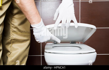 Klempner Problembereich der Toilette zeigen. Händen tragen weiße Handschuhe. Stockfoto