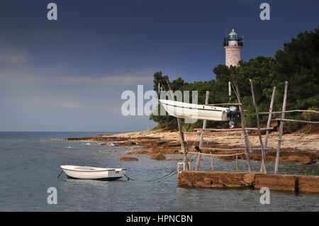 Boote von Savudrija Boote von traditionellen hölzernen Kranen mit Leuchtturm im Hintergrund hängen hängen.  Hängende Boote von Istrien, Kroatien. Angelboot/Fischerboot Stockfoto