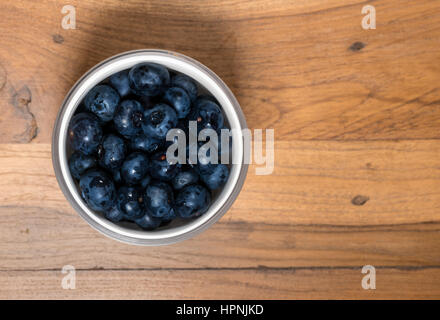 Antenne oder Top Blick auf eine weiße Glasschale Bio Heidelbeeren frisch gewaschen und sitzen auf dem alten Holztisch Oberfläche Stockfoto