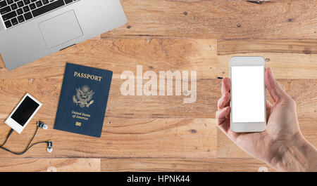 Sauber und ordentlich Holz Schreibtisch mit Ausrüstung bereit für die Reise inkl. Kamera, Laptop, Musik-Player, Reisepass und Smartphone in der hand Stockfoto