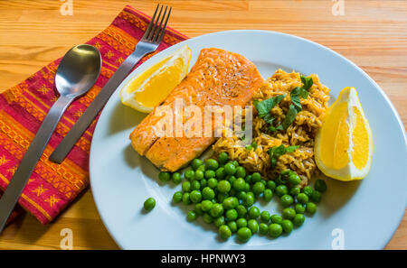 Pochierter Lachs mit braunem Reis, frischen grünen Erbsen, Kräutern und Zitrone. Stockfoto