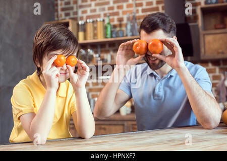 Vater und Sohn spielen mit Zitrusfrüchten in Küche Stockfoto