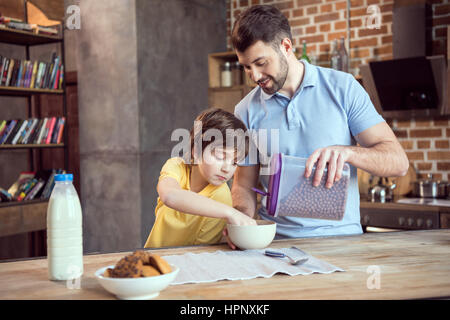 Vater und Sohn vorbereiten Schokolade Mais Kugeln mit Milch Stockfoto