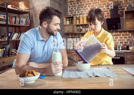 Vater und Sohn vorbereiten Schokolade Mais Kugeln mit Milch Stockfoto