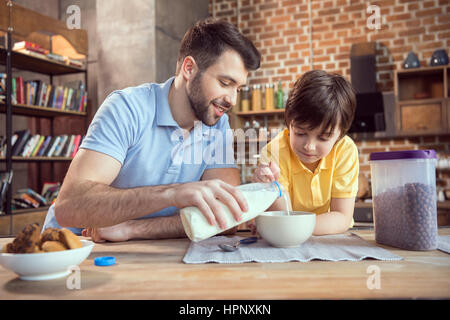 Vater und Sohn vorbereiten Schokolade Mais Kugeln mit Milch Stockfoto