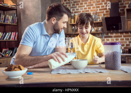 Vater und Sohn vorbereiten Schokolade Mais Kugeln mit Milch Stockfoto