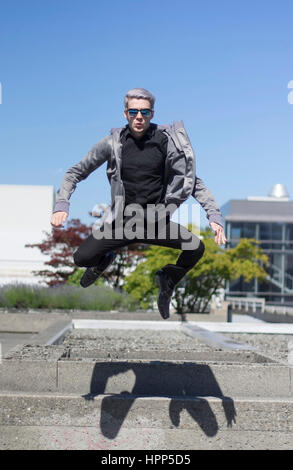 junge Mann trägt schwarze springen weg von der Oberseite der Treppe, sieht aus wie er fliegt Stockfoto