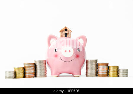 Kleines Haus und Piggy Einsparungen mit Stapel von Münzen Geld auf weißem Hintergrund. Einsparungen für Wohnkonzept. Stockfoto