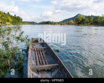 Boot auf der Seite eines Flusses, umgeben von Pflanzen und Vegetation in blauer Himmel Wolken landschaftliche Umgebung Stockfoto