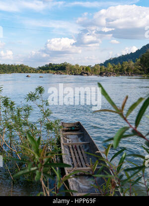 Boot auf der Seite eines Flusses, umgeben von Pflanzen und Vegetation in blauer Himmel Wolken landschaftliche Umgebung Stockfoto