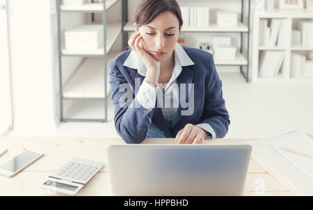 Deprimiert, gelangweilt Geschäftsfrau arbeiten an Schreibtisch und Vernetzung mit einem Laptop, langweiligen Job-Konzept Stockfoto
