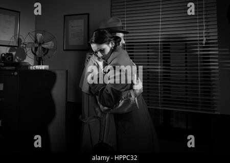 Detective trösten und umarmt eine junge Frau in seinem Büro, Film-Noir-Szene. Stockfoto