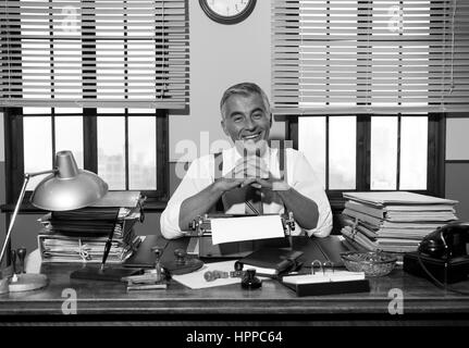 Lächelnde Reporter arbeiten am Schreibtisch mit Vintage Schreibmaschine, 1950er-Jahre Stil. Stockfoto