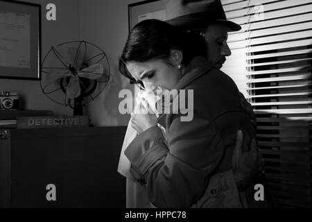 Detective trösten und umarmt eine junge Frau in seinem Büro, Film-Noir-Szene. Stockfoto