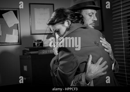 Detective trösten und umarmt eine junge Frau in seinem Büro, Film-Noir-Szene. Stockfoto