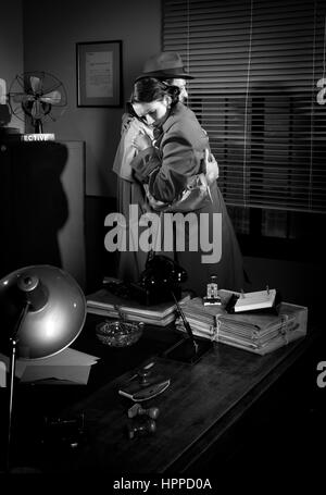 Detective trösten und umarmt eine junge Frau in seinem Büro, Film-Noir-Szene. Stockfoto