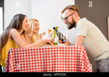 Junge Freunde in bunten T-shirts lässig gekleidet zu Hause zu Mittag mit Pizza und Bier Stockfoto