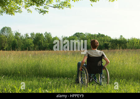 Junger Mann im Rollstuhl an der frischen Luft an einem sonnigen Tag Stockfoto