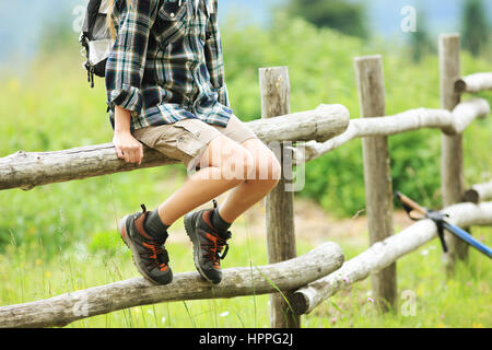 Junge Frau Wanderer sitzen auf einem hölzernen Zaun Stockfoto