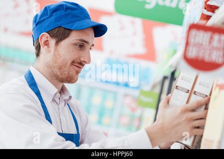 Professionelle Supermarkt Angestellte arbeiten in den Shop-Gang, er ist sortieren von Elementen auf dem Regal Stockfoto