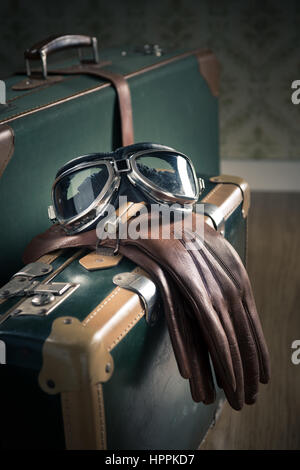 Vintage Pilotenbrille und Lederhandschuhe und Koffer auf dem Boden. Stockfoto