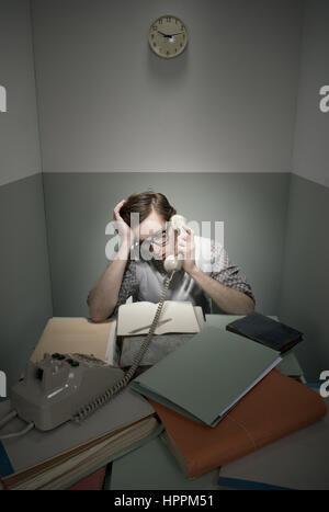 Retro-Geek am Telefon mit unordentlichen Schreibtisch in einem kleinen Raum. Stockfoto