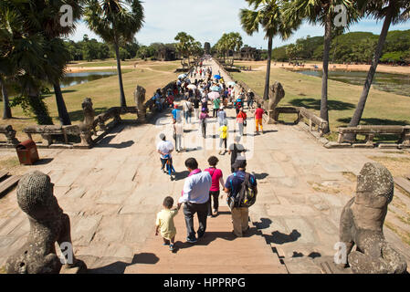 Einem Blick westlich von Touristen verlassen den Haupteingang zu Angkor Wat an einem sonnigen Tag mit blauem Himmel. Stockfoto