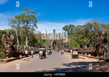 Süden oder südliche Tor oder Gateway zu Angkor Thom mit Tuk Tuk und Touristen auf der Durchreise an einem sonnigen Tag mit blauem Himmel und Vormund Götter aus Stein. Stockfoto