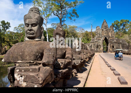 Süden oder südliche Tor oder Tor nach Angkor Thom mit einem Tuk-Tuk an einem sonnigen Tag mit blauem Himmel und steinernen Wächter Götter auf der Durchreise. Stockfoto