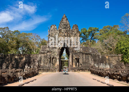 Süden oder südliche Tor oder Tor nach Angkor Thom mit einem Tuk-Tuk an einem sonnigen Tag mit blauem Himmel und steinernen Wächter Götter auf der Durchreise. Stockfoto