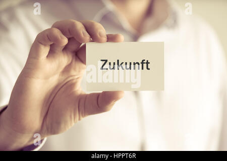 Closeup auf Geschäftsmann hält Textkarte "Zukunft" in deutscher Sprache - Übersetzung: Zukunft, Firmen-Konzept-Image mit soft-Fokus-Hintergrund und Stockfoto