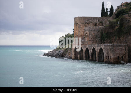 Mittelalterliche Werft mit Bögen und überragt es in mediterranen Stadt Alanya mit dramatischen grauen Wolken Schuss an Wintertag Stockfoto