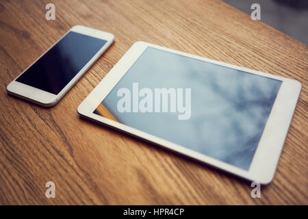 Smartphone und digital-Tablette auf Schreibtisch aus Holz Stockfoto