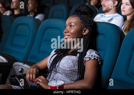 Heute keine Ablenkung. Porträt einer schönen jungen afrikanischen Frau lächelnd Blick auf dem Bildschirm aufmerksam und genießen Sie einen Film auf der lo Stockfoto