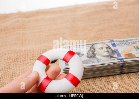 Rettungsring in der Hand über die Banknote Bündel von US-dollar Stockfoto