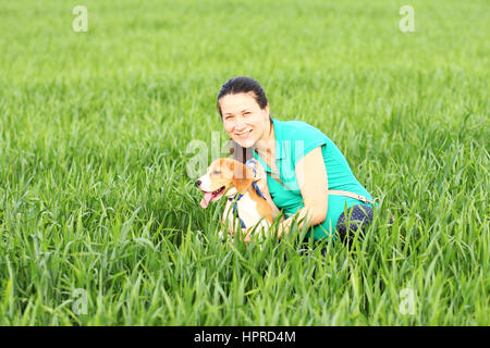 Junge lächelnde Frau mit Beagle Hund auf Wiese Stockfoto