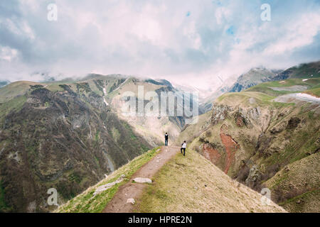 Zwei Touristen sind am Rande der Gudskoye Schlucht In Georgien, Mtiuleti Region fotografiert. Frühling-Berglandschaft. Stockfoto