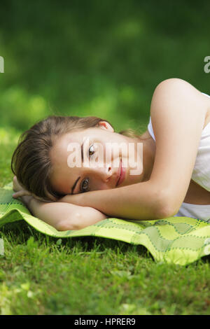 Junge schöne Frau, die Verlegung auf dem Rasen Stockfoto