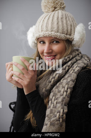 Junge Frau trägt Winterkleidung mit einem heißen Getränk Stockfoto