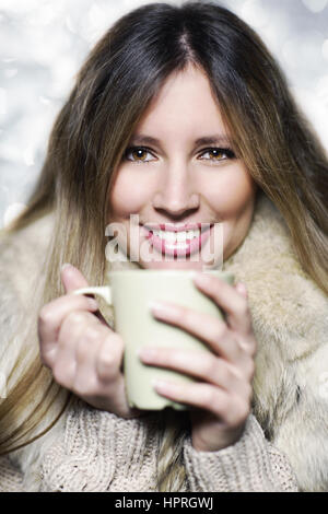 Junge Frau trägt Winterkleidung mit einem heißen Getränk Stockfoto