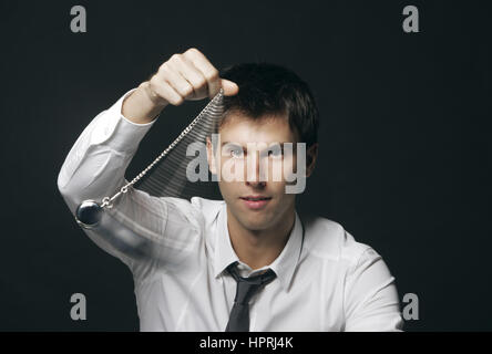 Geschäftsmann hält eine Taschenuhr und schwingen es in der Mode ein Hypnotiseur Stockfoto