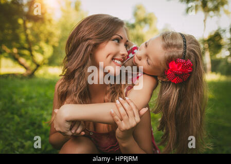 Schöne Mutter und Tochter Spaß im Park im Frühling. Stockfoto