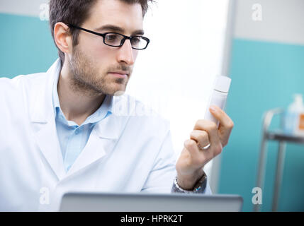 Junger Arzt denken und verschreibungspflichtige Arzneimittel zu prüfen. Stockfoto