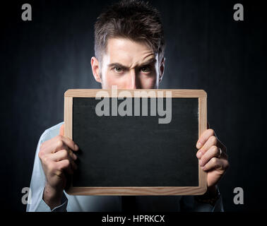 Schönen jungen Mann mit hochgezogenen Augenbrauen hält eine Tafel. Stockfoto